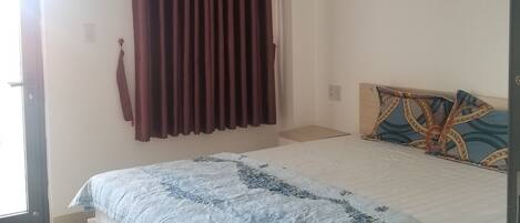 Um quarto com cama, cortinas e cabeceira.