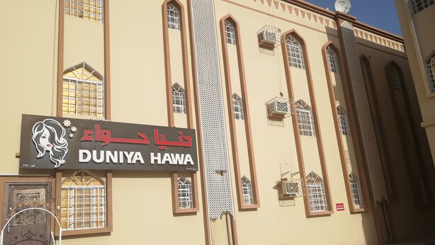Un edificio con un letrero que dice "DUNIYA HAWA" y una antena parabólica en el techo.