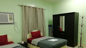Un dormitorio con dos camas, un armario, un espejo y una lámpara de pie.
