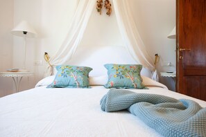 A neatly made bed with two floral pillows, a knitted throw, and a white canopy. - Poggio Ginepro Assisi with private pool, maximum privacy (Assisi)