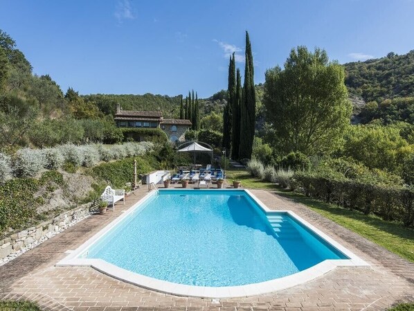 A rectangular swimming pool with a tiled deck, surrounded by greenery and a stone wall. - Poggio Ginepro Assisi with private pool, maximum privacy (Assisi)