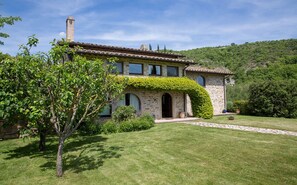 A stone house with a tiled roof, a chimney, and a well-maintained lawn. - Poggio Ginepro Assisi with private pool, maximum privacy (Assisi)