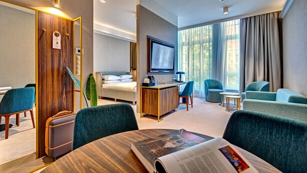 A modern hotel room with a bed, a desk, a TV, and seating areas. - Haston Old Town (Wroclaw)