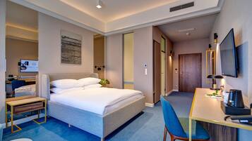 A hotel room with a bed, desk, chair, and a television.