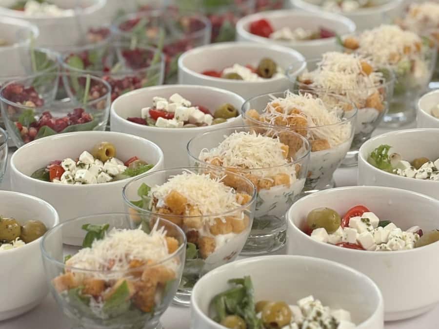 Diversas pequenas tigelas de vidro com diferentes tipos de comida, provavelmente uma seleção de buffet ou aperitivos.