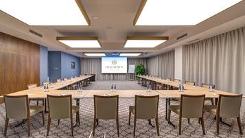 A conference room with a long table, chairs, a projector screen displaying "OLD TOWN HASTON", and a patterned carpet.