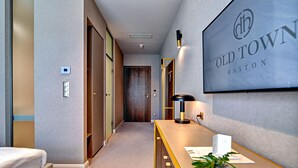 A hotel reception area with a reception desk, a framed sign reading "Old Town Hastings," and a hallway leading to rooms. - Haston Old Town (Wroclaw)