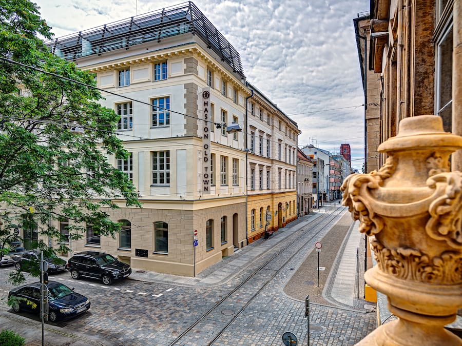 Une vue de rue avec des immeubles, un tramway et des voitures garées.
