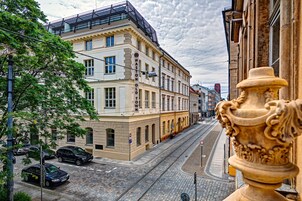 Straßenansicht mit Gebäuden, einer Straßenbahn und parkenden Autos.