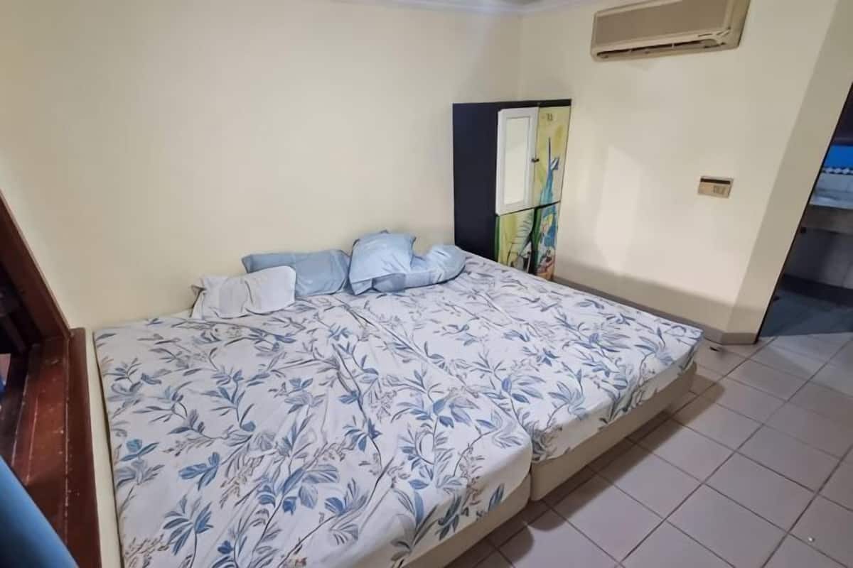 Une chambre à coucher comprenant un lit, des oreillers, une armoire et un climatiseur fixé au mur.