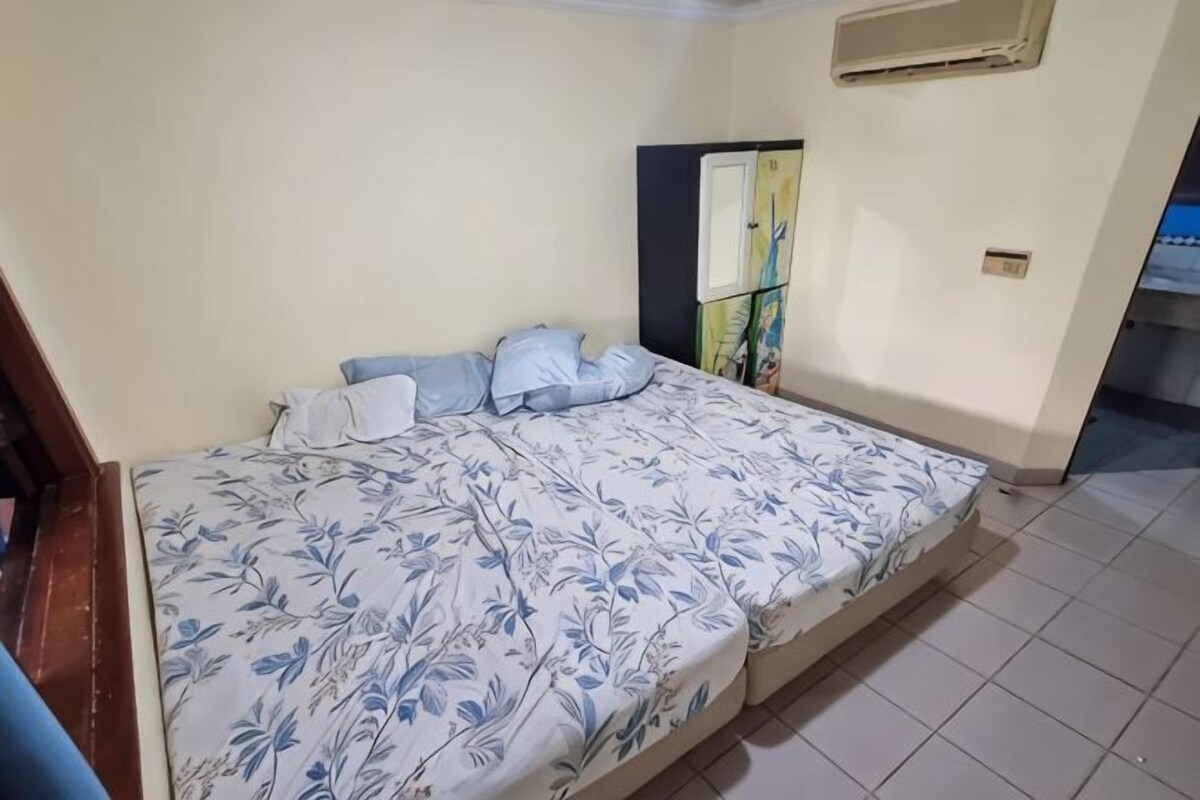 Un dormitorio con cama, almohadas, un armario y un equipo de aire acondicionado instalado en la pared.