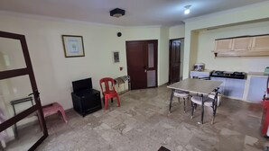 Una cocina compacta con comedor, un refrigerador, una estufa a gas y una puerta que da a otra habitación.