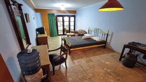 Un dormitorio con cama, escritorio, silla, dispensador de agua y tanque de gas.