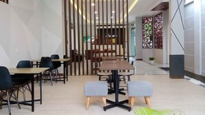 A modern dining area with tables and chairs, a decorative partition, and a view into another room. - Alzara Hotel Syariah (Wonosari)