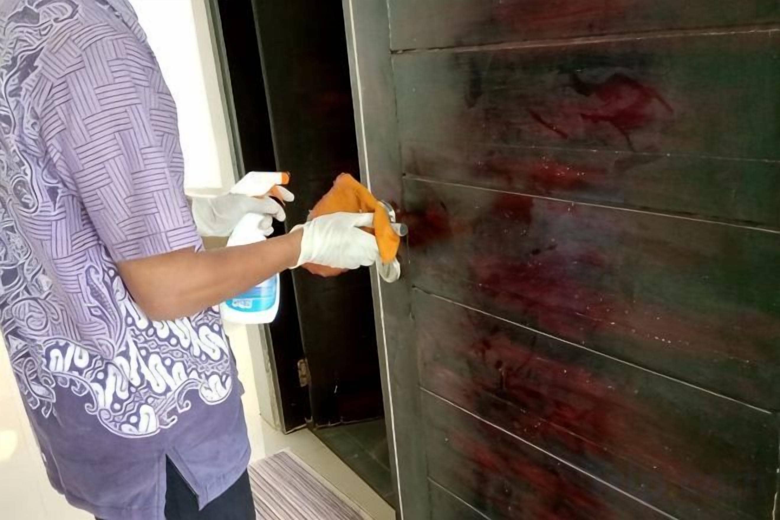 A person cleaning a door with a spray bottle and cloth.