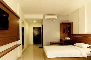A hotel room with a bed, a TV mounted on the wall, a wardrobe, and a bedside table. - Alzara Hotel Syariah (Wonosari)