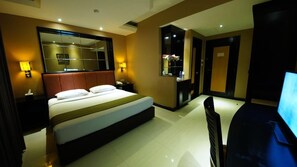 A hotel room with a large bed, bedside lamps, a television, and a mirror. - Tematik Hotel Pluit (Jakarta)
