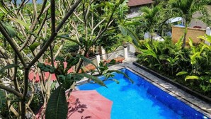 A swimming pool surrounded by lush greenery and a white fence. - Dewivilla Hotel (Padangbai)