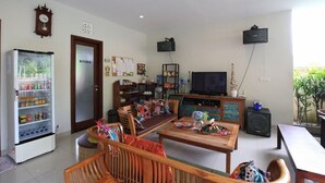 A living room with a TV, a refrigerator, a wooden coffee table, and a sofa. - Dewivilla Hotel (Padangbai)