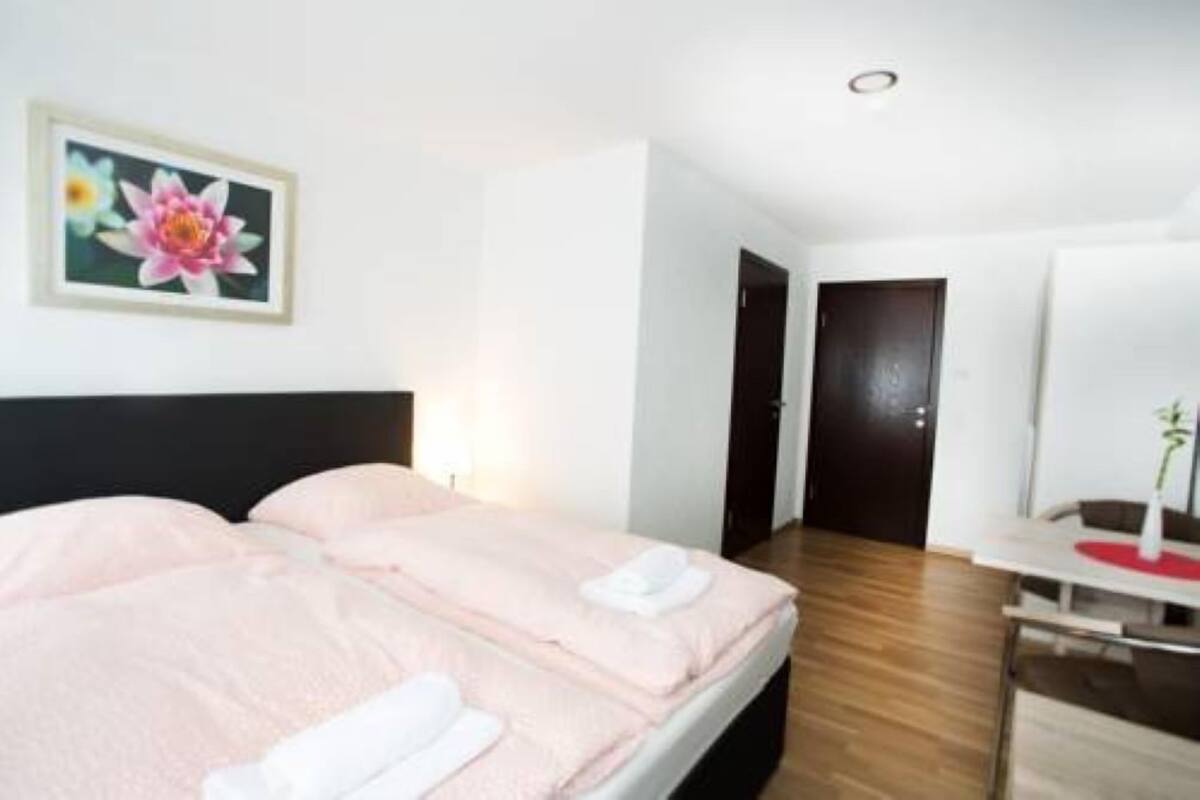 A hotel room with a bed, a desk, and a wall-mounted painting.