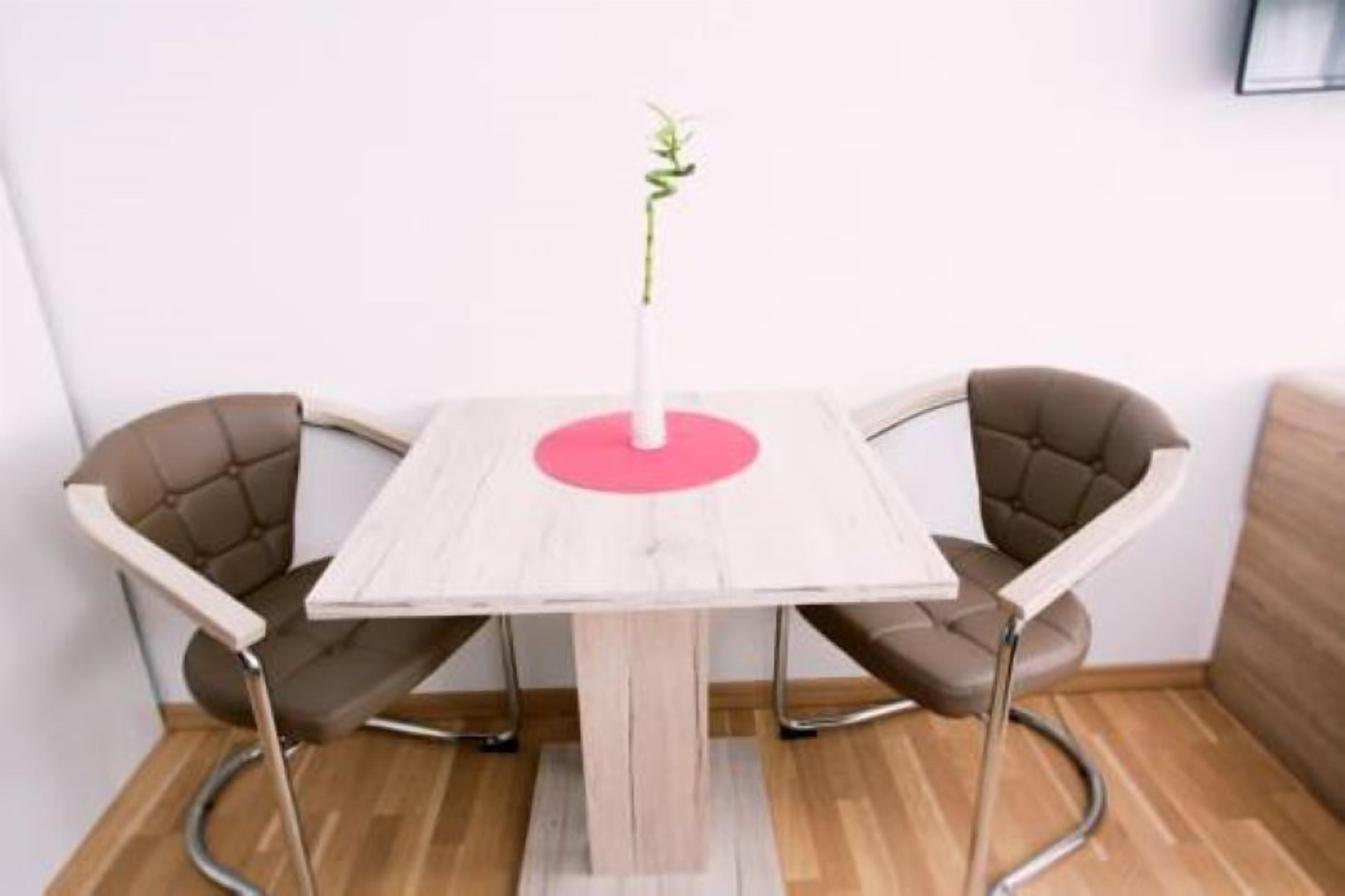 A small, modern room with a wooden table and two brown chairs.