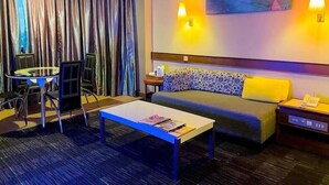 A hotel room with a round table, two chairs, a sofa, a coffee table, and a painting on the wall. - Hotel Grand Crystal Kedah (Alor Setar)