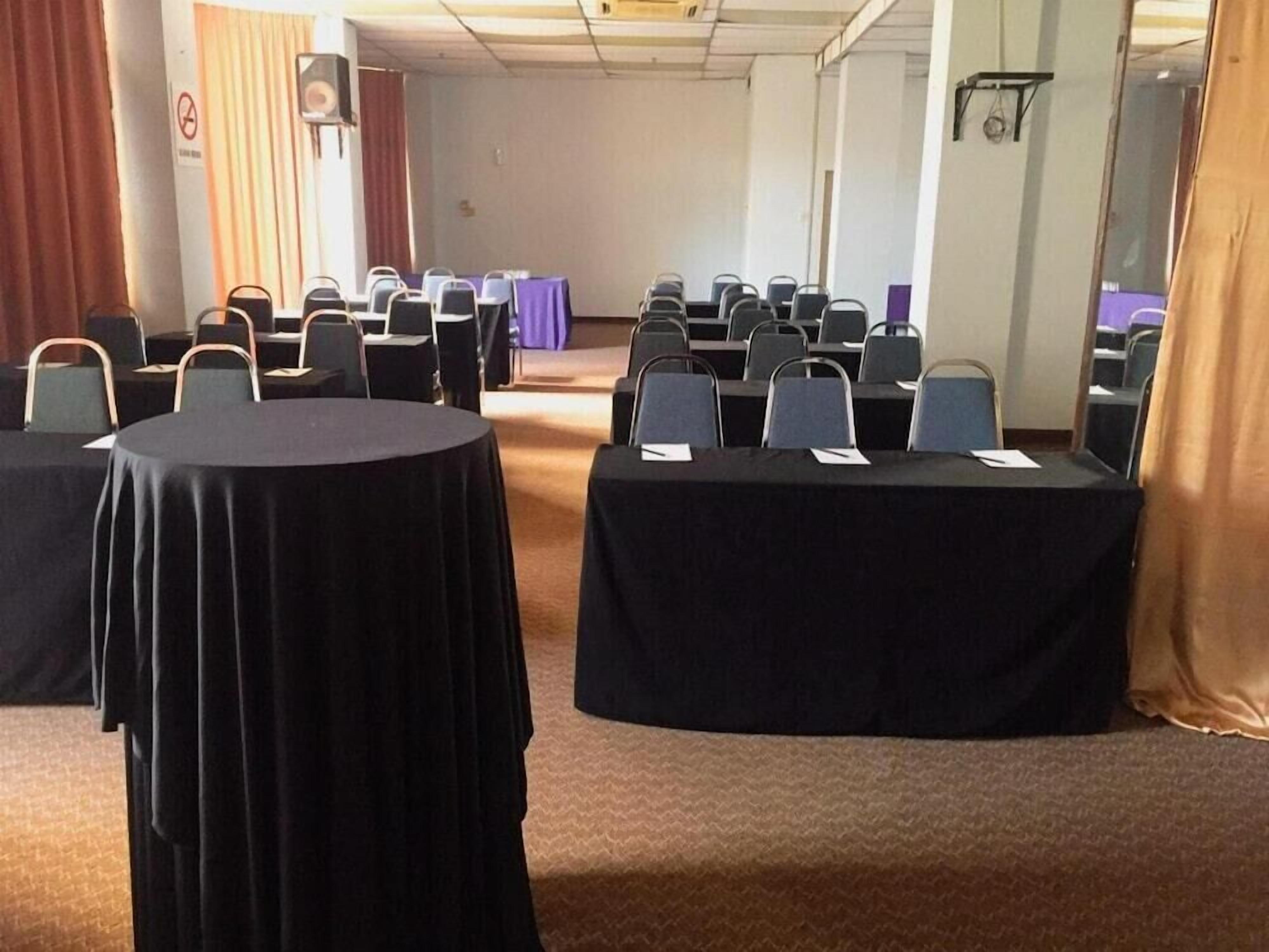 A conference room with round tables and chairs, a stage, and a curtain.