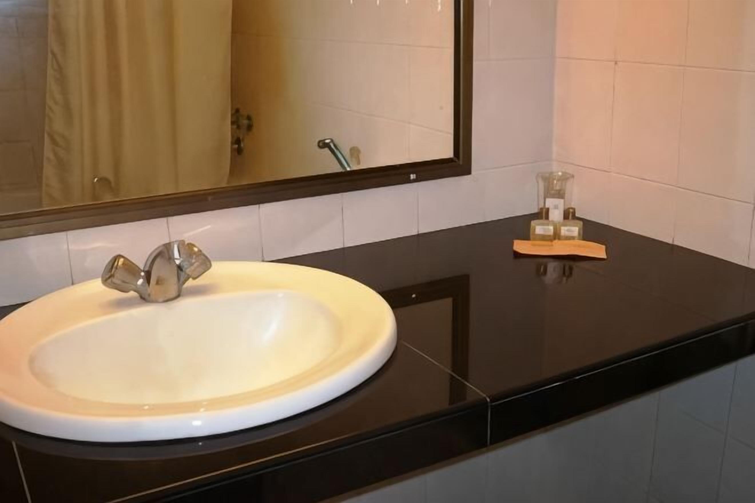 Ein Badezimmer mit Waschbecken, schwarzer Arbeitsplatte und Spiegel.