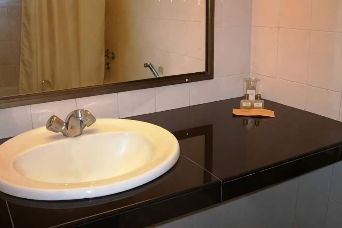 Ein Badezimmer mit Waschbecken, schwarzer Arbeitsplatte und Spiegel.