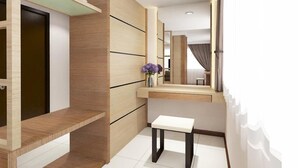 A modern bathroom with a wooden vanity, a mirror, and a white bench. - Hotel Anika (Kluang)