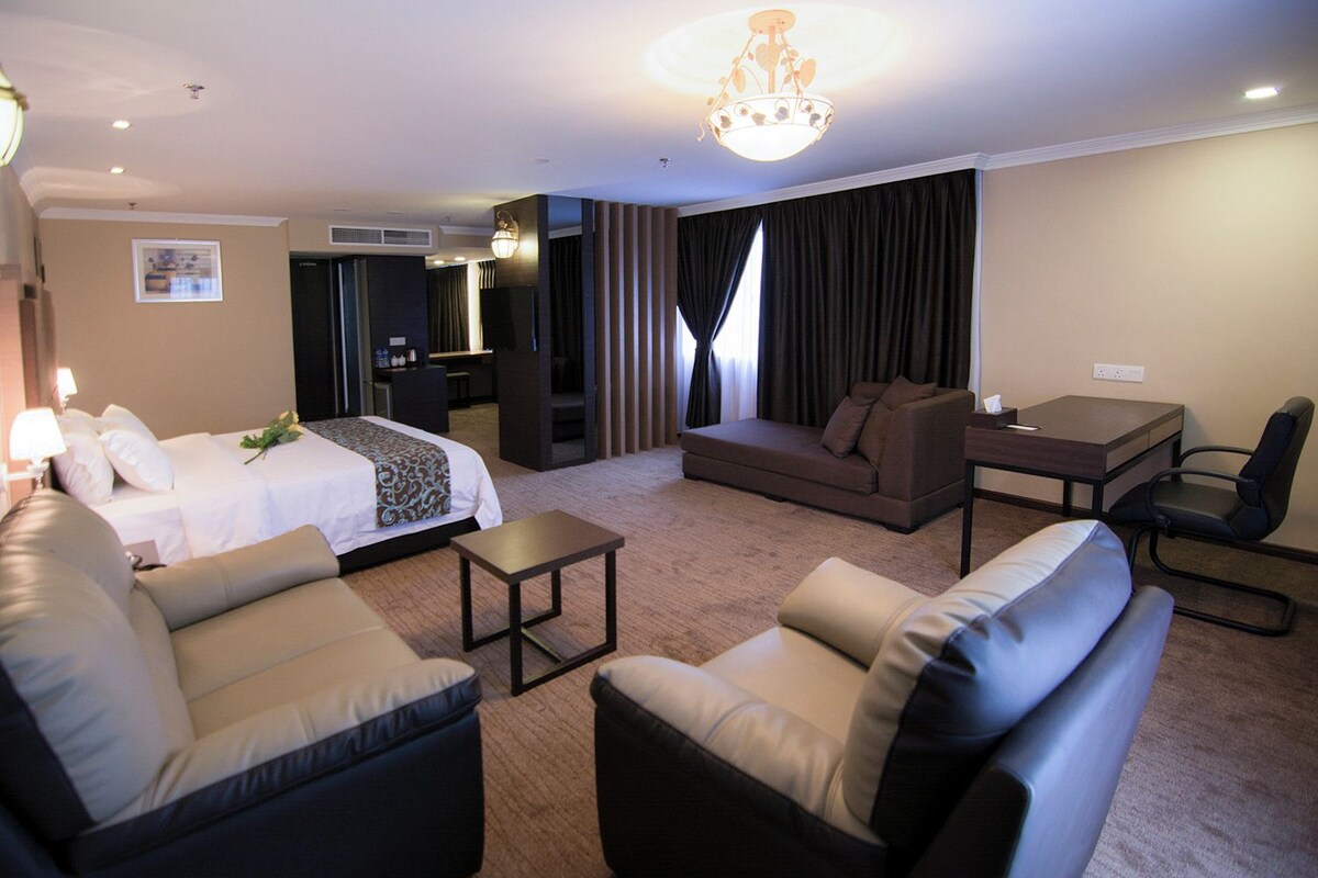 A hotel room with a bed, two sofas, a desk, and a chair.