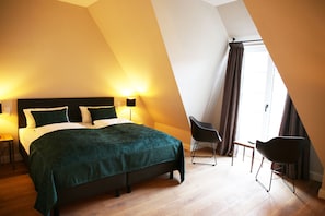 Une chambre à coucher avec un lit, des tables de chevet, une chaise et une fenêtre avec des rideaux.