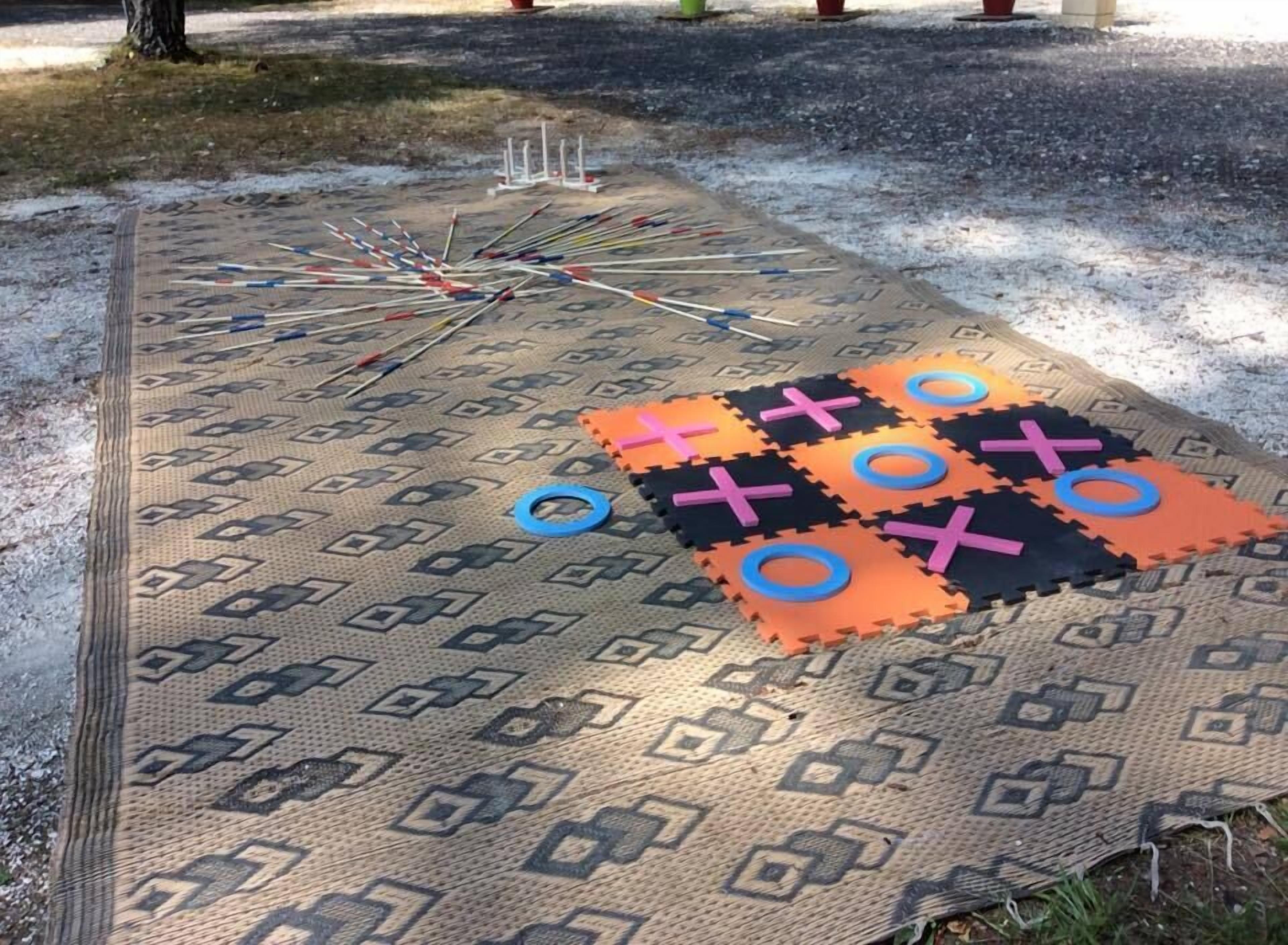 Un jeu de société installé sur un tapis à motifs, à l’extérieur.