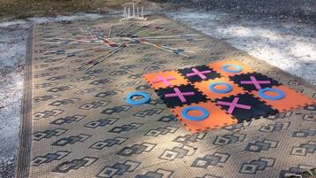 Un jeu de société installé sur un tapis à motifs, à l’extérieur.