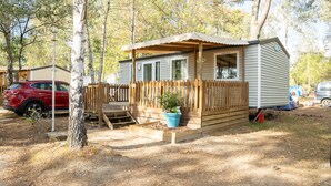 A mobile home with a porch, a small deck, and a potted plant. - Camping Le Chene Du Lac (Bayas)
