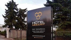 Une grande enseigne pour l’hôtel Miodowy, ornée d’un logo hexagonal, indiquant qu’il s’agit d’un hôtel doté d’une salle de conférence et d’un centre d’affaires.