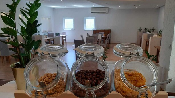 Un buffet de petit-déjeuner avec trois bocaux en verre contenant différents types de céréales, une plante en pot et une pancarte indiquant « Lubella ».