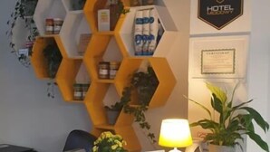 Un comptoir d'accueil avec une étagère hexagonale jaune où sont exposés divers objets, une lampe et une petite figurine de lapin.