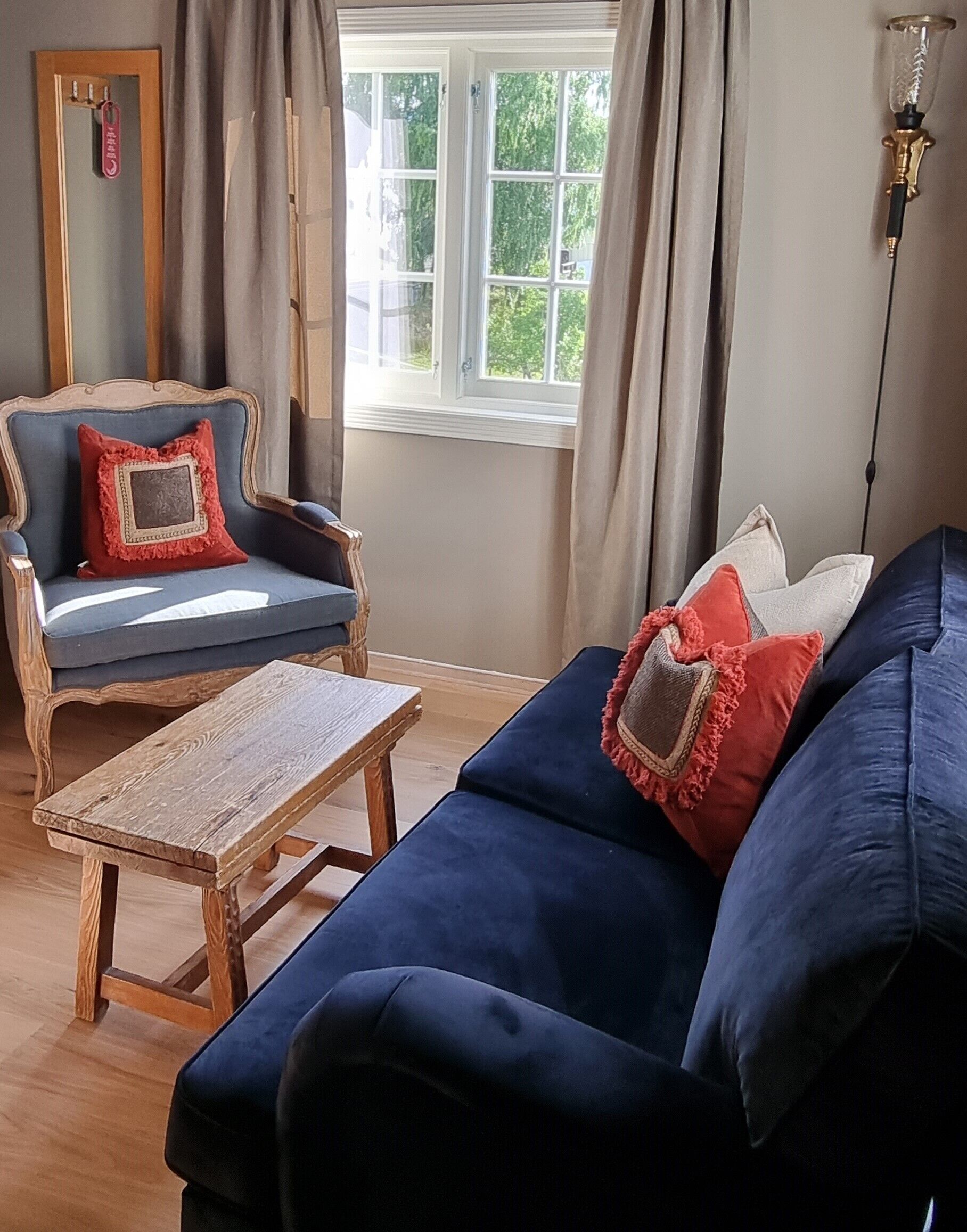 A room with a blue sofa, a wooden coffee table, and a chair with red cushions.