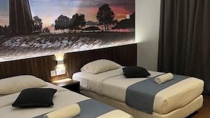 A hotel room with two beds, each with a pillow and a rolled towel. There is a painting above the beds depicting a landscape. - White Lodge (Langkawi)