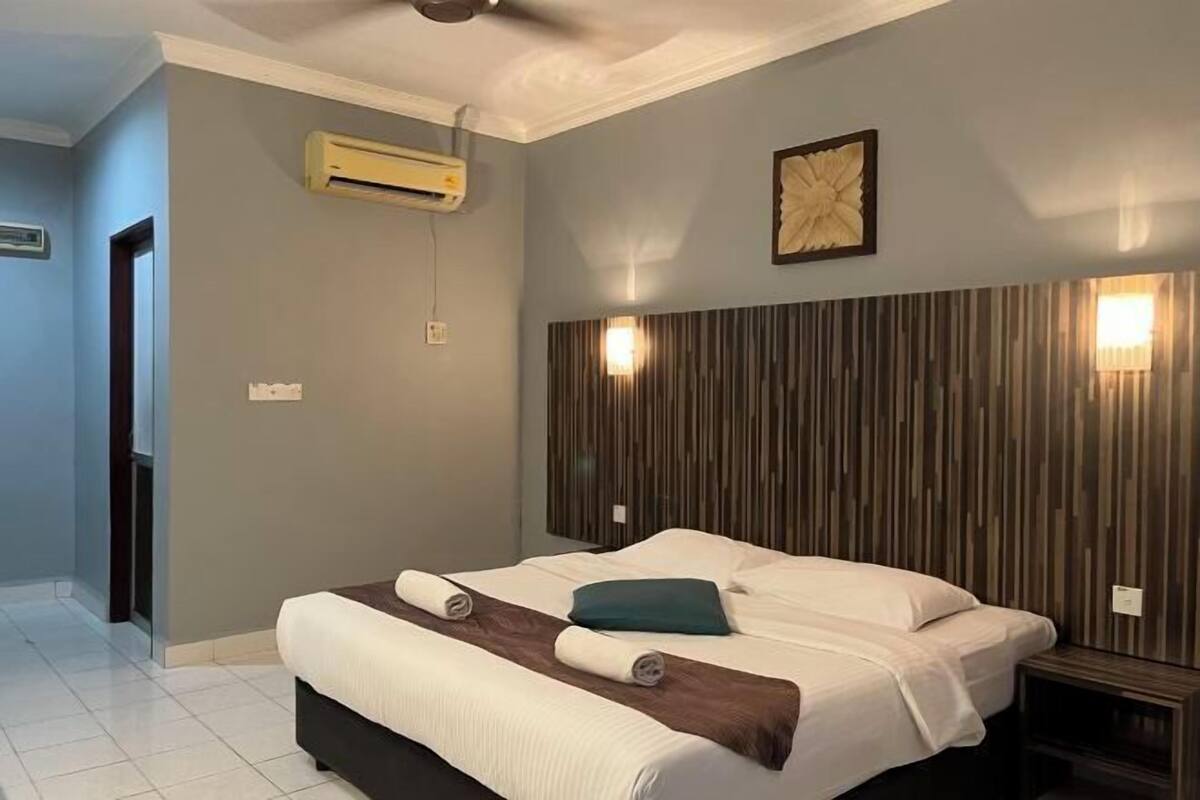 A modern hotel room with a large bed, a wooden headboard, and an air conditioning unit on the wall.