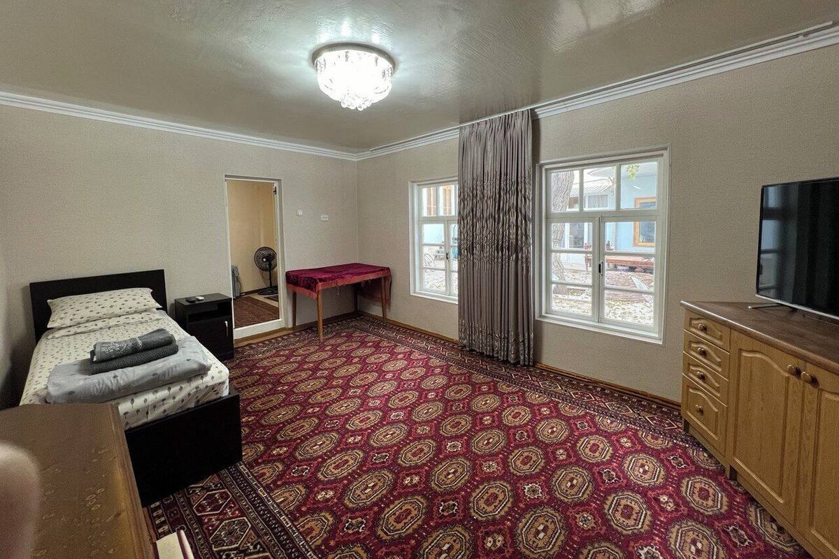 A room with a bed, a desk, a TV, and a patterned carpet.