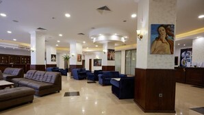 A hotel lobby with a reception desk, seating area, and artwork on the walls. - Hotel Continental (Golden Sands)