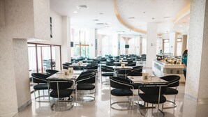 A spacious restaurant with high ceilings, modern black chairs, and a clean, well-lit interior. - Hotel Continental (Golden Sands)