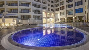 A large indoor swimming pool with a tiled floor, surrounded by a multi-story hotel building with balconies and outdoor seating areas. - Hotel Continental (Golden Sands)
