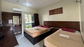 Camera d'albergo con due letti, una scrivania e una finestra vista verde.