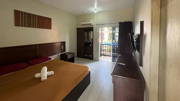 Camera d'albergo con un letto, una TV, una scrivania e una porta scorrevole che dà su un balcone.
