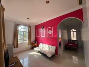 A room with a bed, a sofa, a TV, and a window with curtains. - Mersing Beach Resort (Mersing)