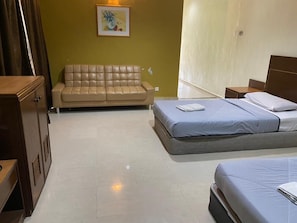 A hotel room with a bed, a sofa, a nightstand, and a wall-mounted picture. - Mersing Beach Resort (Mersing)