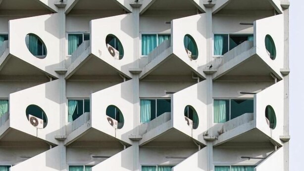 Ein mehrstöckiges Gebäude mit einer geometrischen Fassade, inklusive Balkonen und Rundfenstern.